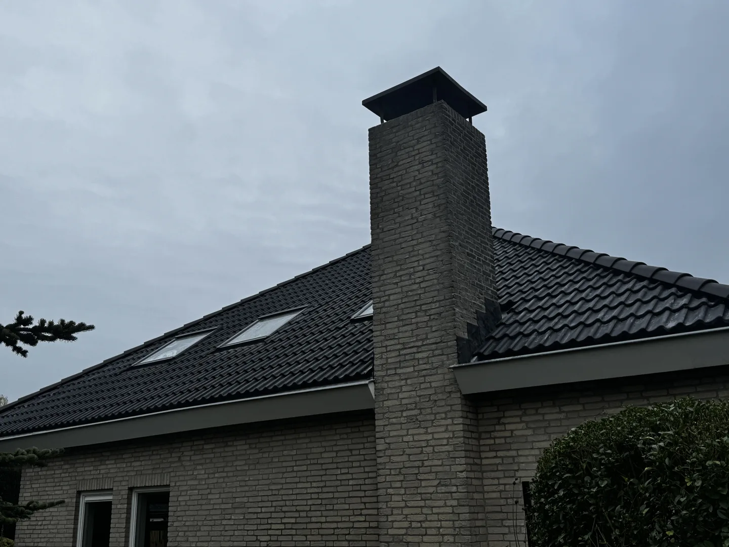 Vernieuwd dakvlak met antraciete dakpannen en schoorsteen in Hedel